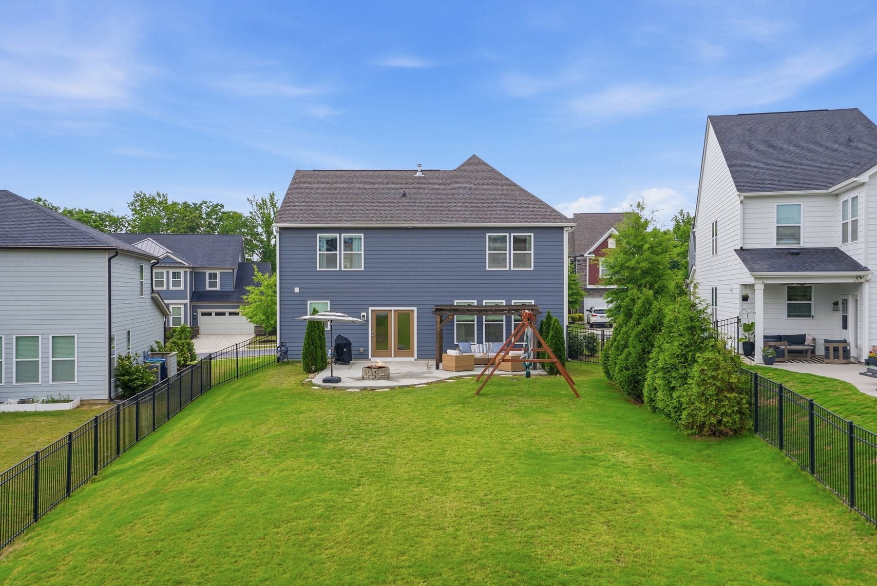 Back yard with a swing set and mature landscaping